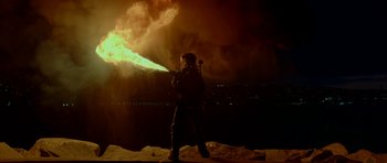 Movie still from “Ema” (2019), directed by Pablo Larraín – A man standing on top of a hill while holding an object in his hand; Extreme Wide shot, Low angle