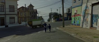 Movie still from “Ema” (2019), directed by Pablo Larraín – A woman and a child walking down a street; Wide shot, High angle