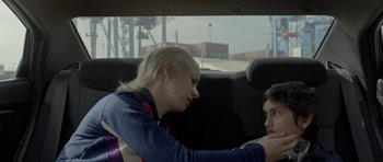 Movie still from “Ema” (2019), directed by Pablo Larraín – Two young people sitting in the back seat of a car; Close Up shot, High angle