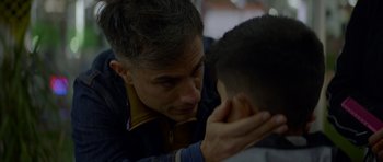 Movie still from “Ema” (2019), directed by Pablo Larraín – A man is touching the ear of a young boy; Close Up shot, Over the shoulder angle