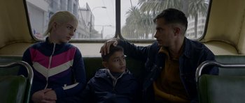Movie still from “Ema” (2019), directed by Pablo Larraín – A man and a woman sitting next to a young boy; Medium shot, Low angle