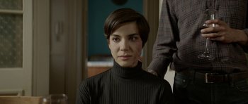 Movie still from “Ema” (2019), directed by Pablo Larraín – A woman with short hair wearing a black shirt; Close Up shot, Over the shoulder angle