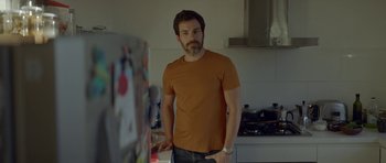 Movie still from “Ema” (2019), directed by Pablo Larraín – A man standing in front of an open refrigerator; Medium shot, Over the shoulder angle