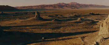 Movie still from “Encounter” (2021), directed by Michael Pearce – An image of a desert with a car parked on the side of the road; Extreme Wide shot, High angle