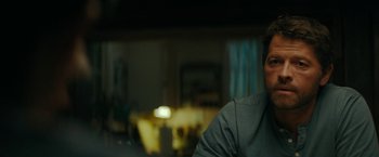 Movie still from “Encounter” (2021), directed by Michael Pearce – A man sitting in front of a tv in a living room; Close Up shot, Over the shoulder angle