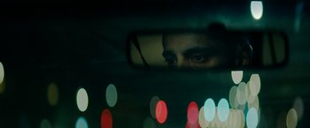 Movie still from “Encounter” (2021), directed by Michael Pearce – A man looking into a rear view mirror of a car; Extreme Close Up shot, Over the shoulder angle