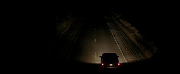 Movie still from “Encounter” (2021), directed by Michael Pearce – A car driving down a dark road at night; Extreme Wide shot, High angle