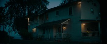 Movie still from “Encounter” (2021), directed by Michael Pearce – A night time picture of a house with the lights lit up; Extreme Wide shot, Low angle