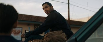 Movie still from “Encounter” (2021), directed by Michael Pearce – A man sitting on top of a motorcycle with a backpack; Close Up shot, Low angle