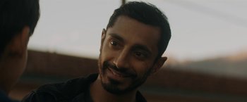 Movie still from “Encounter” (2021), directed by Michael Pearce – A person smiling for a picture; Close Up shot, Over the shoulder angle