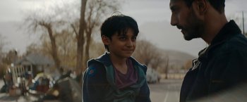 Movie still from “Encounter” (2021), directed by Michael Pearce – A young boy standing next to a man on the side of the road; Close Up shot, Over the shoulder angle