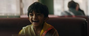 Movie still from “Encounter” (2021), directed by Michael Pearce – A young boy smiling with his mouth wide open; Close Up shot, Over the shoulder angle