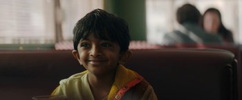 Movie still from “Encounter” (2021), directed by Michael Pearce – A young boy smiles for the camera; Close Up shot, Over the shoulder angle