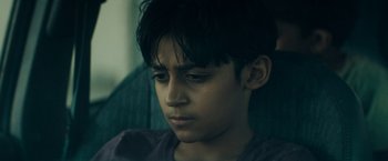 Movie still from “Encounter” (2021), directed by Michael Pearce – A young boy is sitting in a chair looking sad; Close Up shot, Low angle