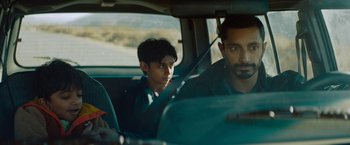 Movie still from “Encounter” (2021), directed by Michael Pearce – A man sitting in a car with a boy in the back seat; Medium shot, Over the shoulder angle