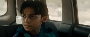 Movie still from “Encounter” (2021), directed by Michael Pearce – A young boy sitting in the back seat of a car; Close Up shot, Over the shoulder angle