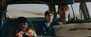 Movie still from “Encounter” (2021), directed by Michael Pearce – A man and two boys sitting in the back of a car; Medium shot, Low angle