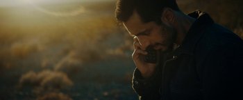Movie still from “Encounter” (2021), directed by Michael Pearce – A man on a cell phone in the dark; Close Up shot, Over the shoulder angle