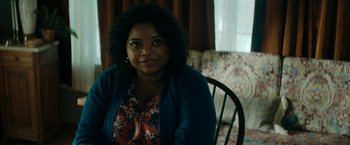 Movie still from “Encounter” (2021), directed by Michael Pearce – A woman sitting on a chair in a room; Close Up shot, Over the shoulder angle