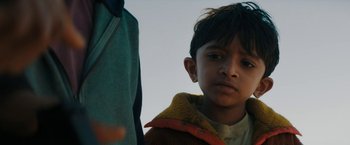 Movie still from “Encounter” (2021), directed by Michael Pearce – A young boy wearing a yellow jacket and standing next to a person; Close Up shot, Low angle
