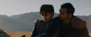 Movie still from “Encounter” (2021), directed by Michael Pearce – A man and a boy are standing in a field; Close Up shot, Low angle