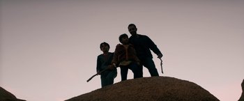 Movie still from “Encounter” (2021), directed by Michael Pearce – A group of people standing on top of a dirt hill; Medium shot, Low angle