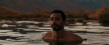 Movie still from “Encounter” (2021), directed by Michael Pearce – A man in a body of water with trees in the background; Close Up shot, Over the shoulder angle