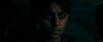 Movie still from “Encounter” (2021), directed by Michael Pearce – A young boy with dark eyes stares into the camera; Close Up shot, High angle