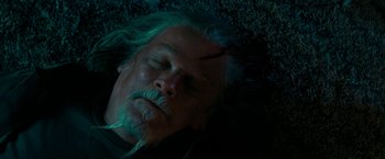 Movie still from “Encounter” (2021), directed by Michael Pearce – An older man with a beard and mustache sleeping on the ground; Close Up shot, Overhead angle