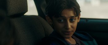 Movie still from “Encounter” (2021), directed by Michael Pearce – A young boy sitting in the back seat of a car; Close Up shot, Over the shoulder angle