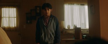 Movie still from “Encounter” (2021), directed by Michael Pearce – A young man standing in a room with a window in the background; Close Up shot, Low angle
