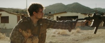 Movie still from “Encounter” (2021), directed by Michael Pearce – A man pointing a gun at something in the distance; Medium shot, Over the shoulder angle