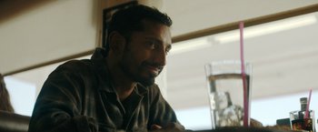 Movie still from “Encounter” (2021), directed by Michael Pearce – A person sitting at a table; Close Up shot, Over the shoulder angle