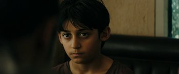 Movie still from “Encounter” (2021), directed by Michael Pearce – A young boy with a brown shirt is looking at the camera; Close Up shot, High angle