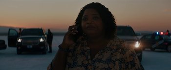 Movie still from “Encounter” (2021), directed by Michael Pearce – A woman talking on a cell phone at sunset; Medium shot, Over the shoulder angle