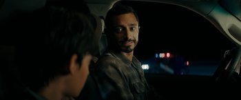Movie still from “Encounter” (2021), directed by Michael Pearce – A man sitting in the back seat of a car at night; Close Up shot, Over the shoulder angle