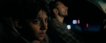 Movie still from “Encounter” (2021), directed by Michael Pearce – A man and a boy sitting next to each other in the dark; Close Up shot, Over the shoulder angle
