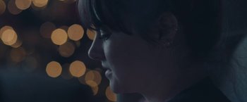 Movie still from “Endings, Beginnings” (2019), directed by Drake Doremus – A woman's face with lights in the background; Extreme Close Up shot, Over the shoulder angle