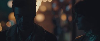 Movie still from “Endings, Beginnings” (2019), directed by Drake Doremus – A man standing in front of some lights in the dark; Extreme Close Up shot, Over the shoulder angle