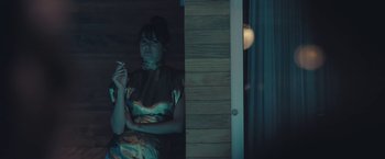 Movie still from “Endings, Beginnings” (2019), directed by Drake Doremus – A woman standing in front of a door holding a cell phone; Medium shot, Low angle