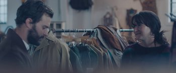 Movie still from “Endings, Beginnings” (2019), directed by Drake Doremus – A row of jackets hanging on a rack; Medium shot, Over the shoulder angle