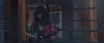Movie still from “Endings, Beginnings” (2019), directed by Drake Doremus – A woman holding a bouquet of flowers while looking at her phone; Medium shot, High angle