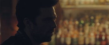 Movie still from “Endings, Beginnings” (2019), directed by Drake Doremus – A man's face in front of bottles; Close Up shot, Over the shoulder angle