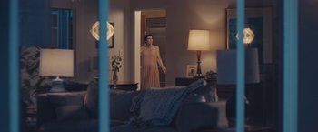 Movie still from “Endings, Beginnings” (2019), directed by Drake Doremus – A woman standing in front of a mirror in a living room; Wide shot, Over the shoulder angle