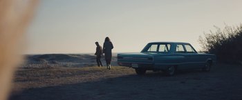 Movie still from “Endings, Beginnings” (2019), directed by Drake Doremus – Two people walking in a field next to an old car; Extreme Wide shot, High angle