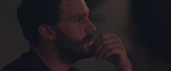 Movie still from “Endings, Beginnings” (2019), directed by Drake Doremus – A man with a beard is looking at something in the dark; Close Up shot, Over the shoulder angle