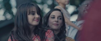 Movie still from “Endings, Beginnings” (2019), directed by Drake Doremus – Two young women sitting next to each other in front of trees; Close Up shot, Over the shoulder angle