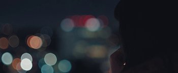 Movie still from “Endings, Beginnings” (2019), directed by Drake Doremus – A woman standing in front of a city at night; Extreme Close Up shot, High angle