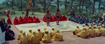 Movie still from “Enter the Dragon” (1973), directed by Robert Clouse – A group of people sitting on the ground in front of a group of people; Extreme Wide shot, High angle