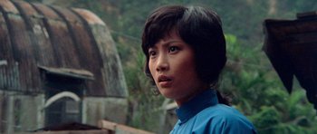 Movie still from “Enter the Dragon” (1973), directed by Robert Clouse – A woman in a blue shirt is looking at the camera; Close Up shot, Low angle